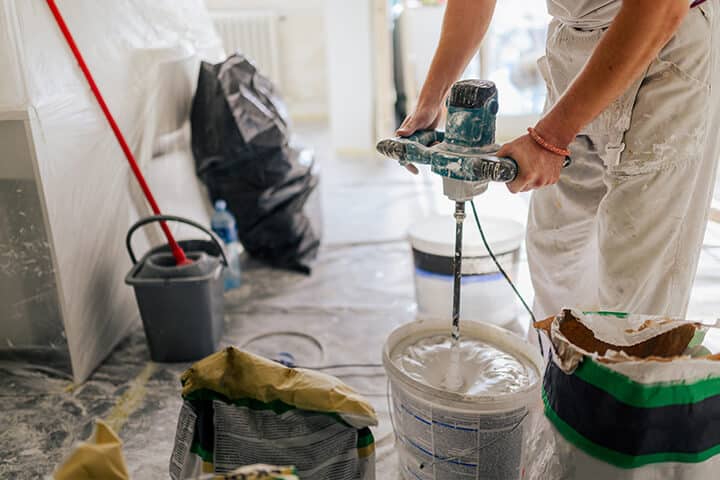 worker's hands mixing plaster and preparing for skim coating walls