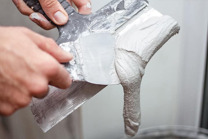 man removing excess plaster from the spatula